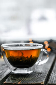 A clear glass cup of tea on a wooden table