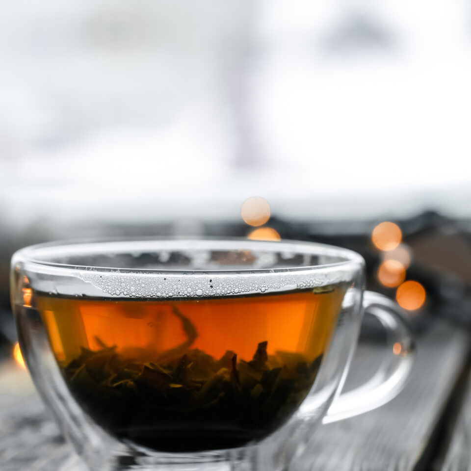 A clear glass cup of tea on a wooden table