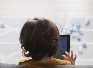 A child seen from behind, holding a tablet