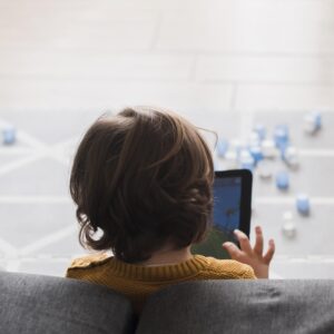 A child seen from behind, holding a tablet